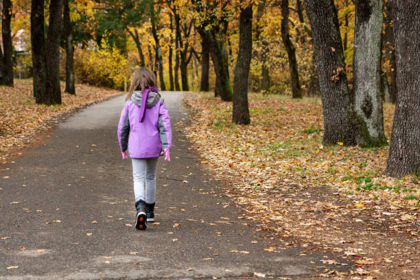 Rear view of gilr walking in the park during autumn day.