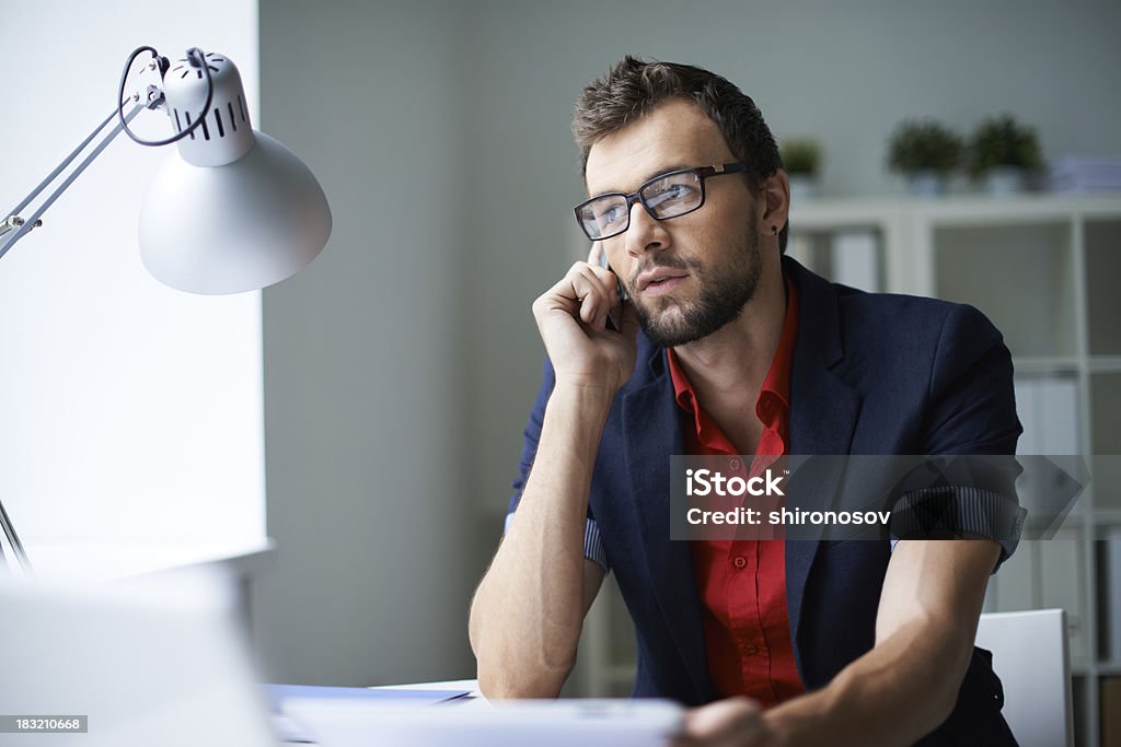 Business call Handsome businessman in smart casual and eyeglasses speaking on the phone in office Talking Stock Photo