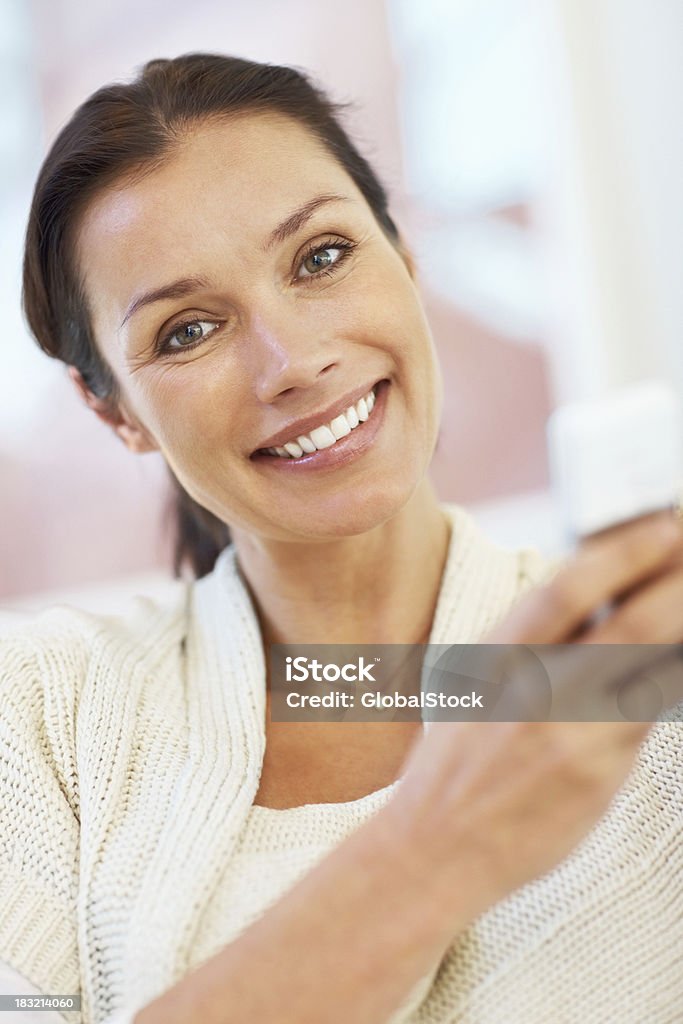 Sonriendo medio de mujer sosteniendo un teléfono móvil - Foto de stock de Adulto libre de derechos