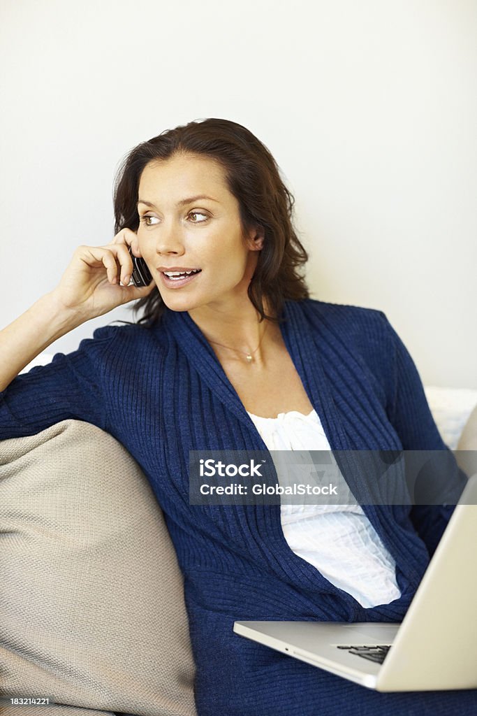 Medio de chica con ordenador portátil al hablar sobre el cellphone - Foto de stock de Actividades recreativas libre de derechos