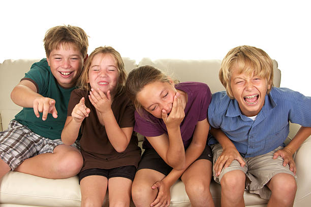 istock Four Kids on a Couch Watching Something Funny and Laughing 183214391