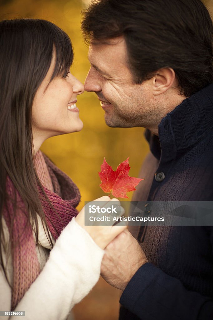Romantyczna para uśmiechając się trzymając jesień Liść na zewnątrz jesienią - Zbiór zdjęć royalty-free (20-29 lat)