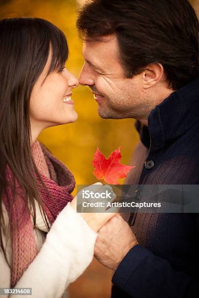 Romantyczna Para Uśmiechając Się Trzymając Jesień Liść Na Zewnątrz Jesienią - zdjęcia stockowe i więcej obrazów 20-29 lat