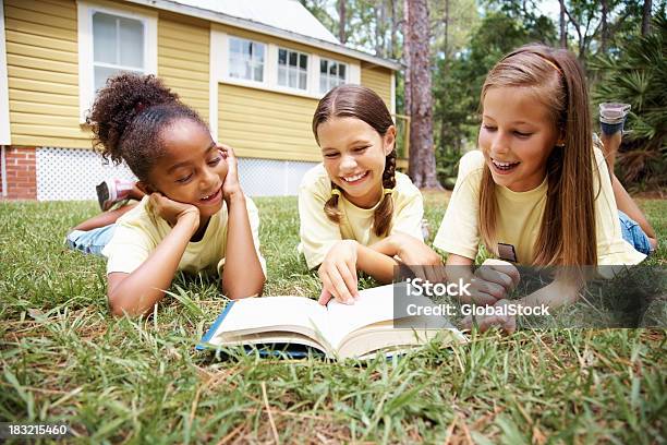 Веселый Молодой Девушки Чтение Книги Лежа На Лужайке — стоковые фотографии и другие картинки Беззаботный