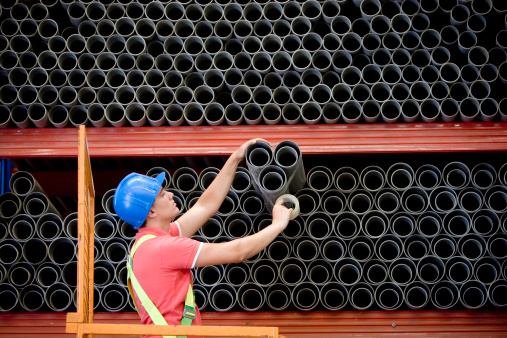 Worker cuting blue pvc pipe in construction site.
