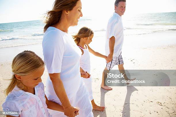 Famiglia Con Due Bambini Tenendo Le Mani Mentre Si Cammina Sulla Spiaggia - Fotografie stock e altre immagini di Bambino