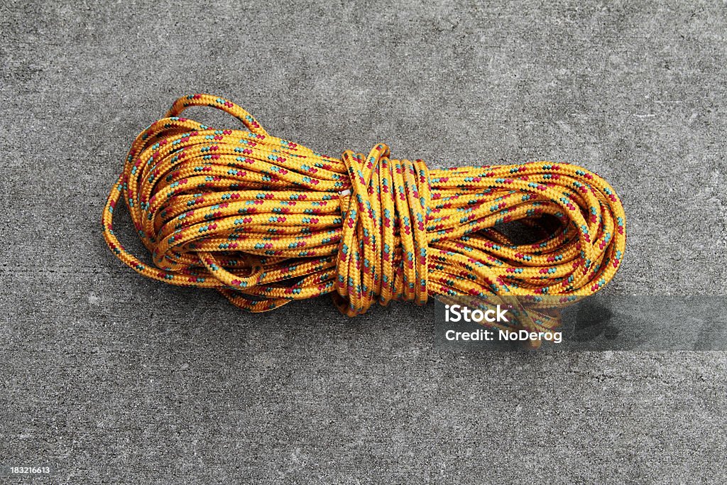 Coil of rope Coil of orange colored rope on concrete background. Color Image Stock Photo