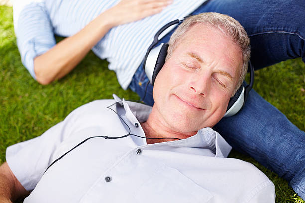 istock An elderly man wearing headphones while resting on woman's lap 183216825