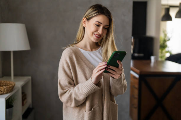 istock Smiling young female using mobile phone app playing game, shopping online, ordering delivery 1832187203