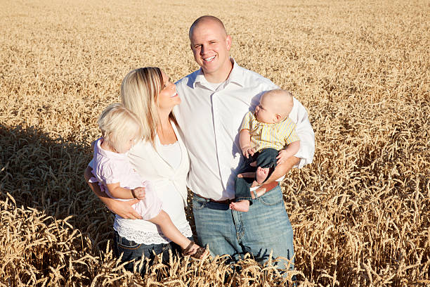 Rural Family Portrait Portrait of a young family of four standing in a field of golden wheat. mormon woman photos stock pictures, royalty-free photos & images