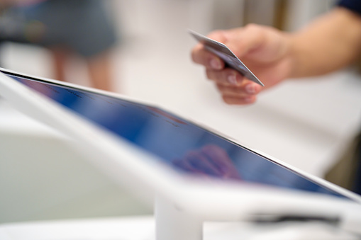 Asian woman contactless payment with credit card  in a shopping mall close-up