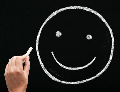 sketching smiling face on blackboard