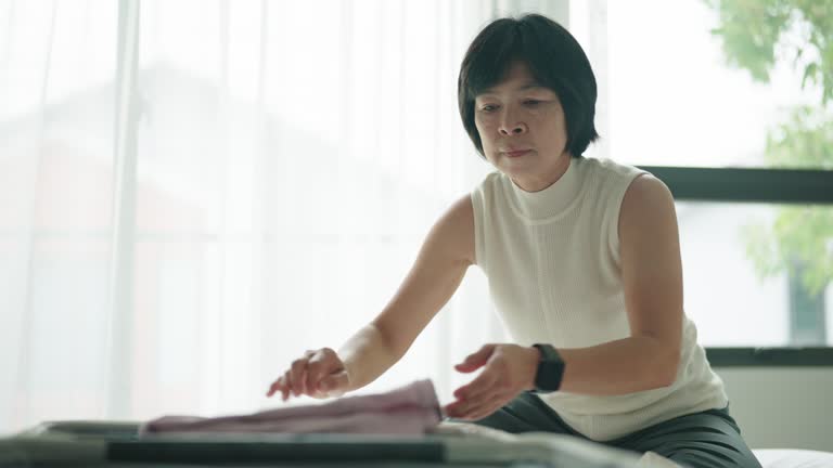 Asian woman packing her suitcase.