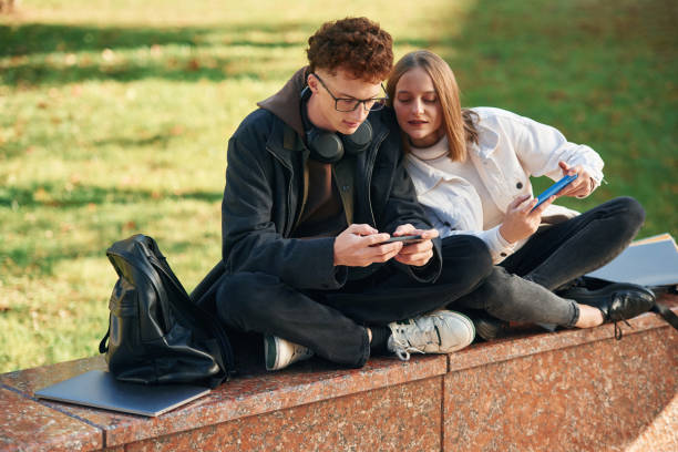 istock Playing games by using smartphones. Two young students are together outdoors 1832225422