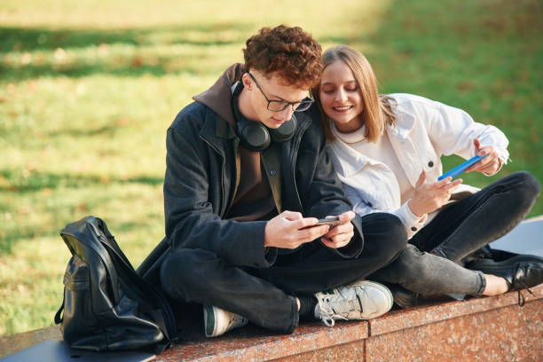 istock Playing games by using smartphones. Two young students are together outdoors 1832225426