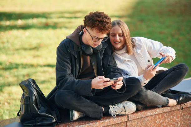 istock Playing games by using smartphones. Two young students are together outdoors 1832225804