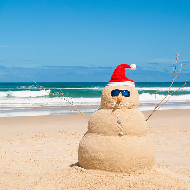 Snowman resists melting process on beach stock photo