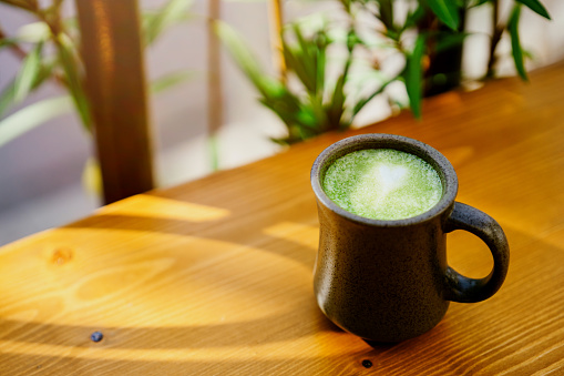 Matcha green tea in ceramic cup on the wooden table.