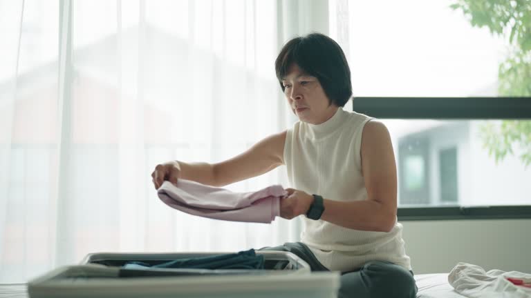 Asian woman packing her suitcase.