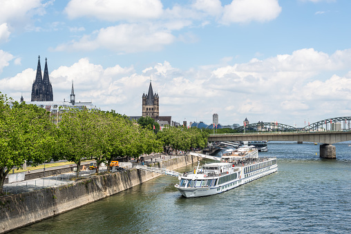 Cologne, Germany - June 11, 2022: Cologne city skyline in summer with a bridge over the Rhine River and passenger ship, North Rhine-Westphalia, Germany.