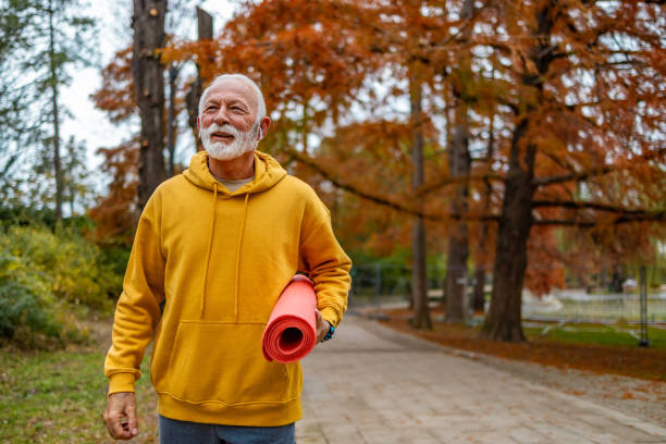 istock Senior man holding exercise mat while walking outdoors. 1832273331