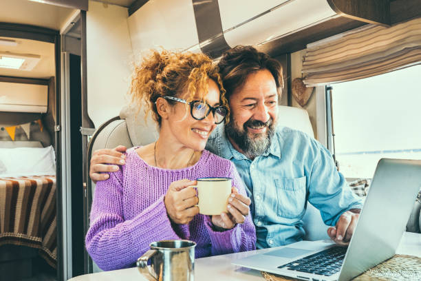 istock Modern couple use together laptop inside camper van. Computer leisure people surfing the web. Traveler planning next destination smiling and enjoying freedom living off grid. Digital nomad concept 1832279749