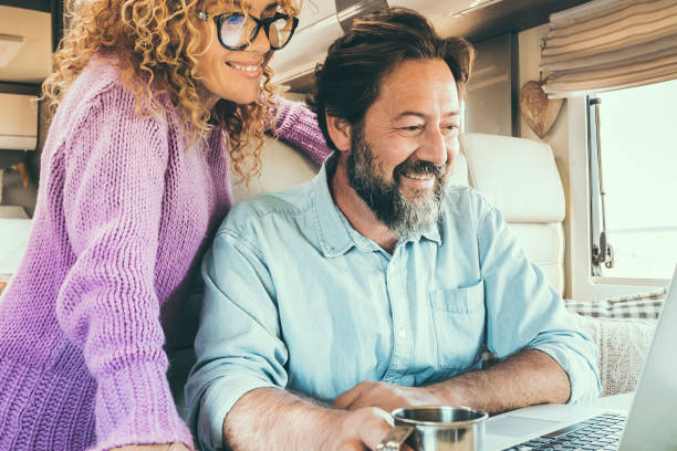 istock Modern travel couple enjoy connection technology using laptop inside a camper van home. Alternative office and house people lifestyle. Digital nomad smart working man and woman trip 1832295068