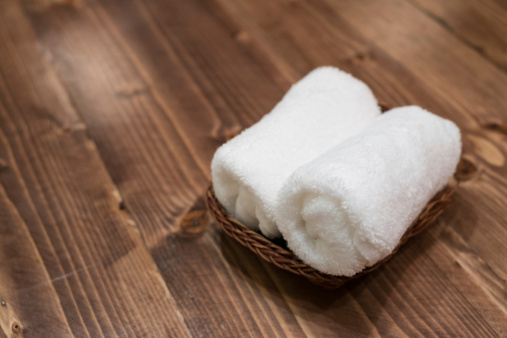 Basket of pure white towels on the wooden table