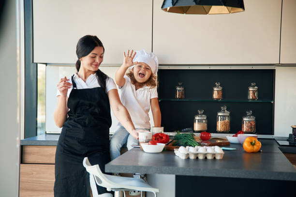 istock Front view. Mother with her daughter are preparing food on the kitchen 1832310548