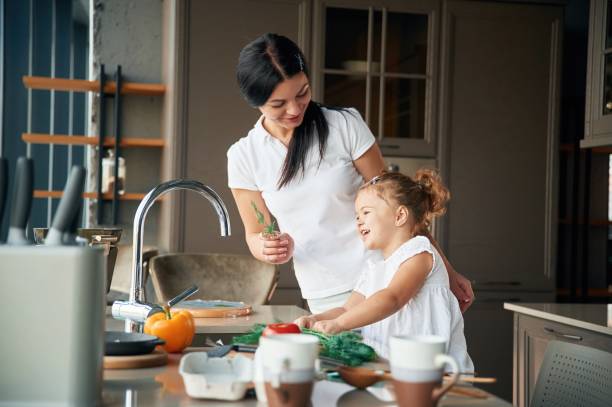 istock Process of learning. Mother with her daughter are preparing food on the kitchen 1832313362