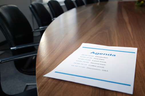 Printed agenda on a stylish boardroom table with focus on the word 'agenda'