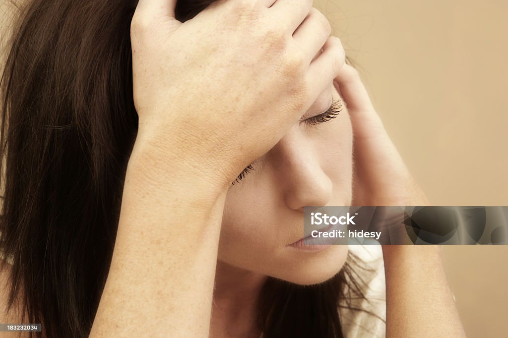 Woman suffering from a migraine on tan background Woman with a headache 20-24 Years Stock Photo