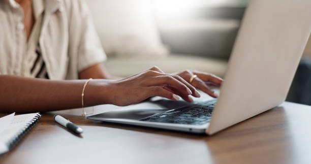 istock Desk, hands typing and laptop in home for remote work, internet search or blog. Closeup, computer and woman on keyboard at table in living room, writing email and communication on digital technology 1832320710