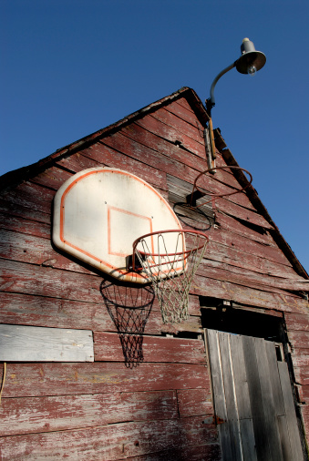 Basketball hoop on the side of a old barn