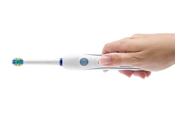 Woman holding an electric toothbrush in her hand. Isolated on a white background.