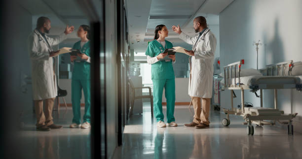 istock Doctors, man and woman in documents, corridor and planning for surgery, advice or tablet in hospital. Medic, nurse and teamwork with chat, mentorship or brainstorming for medical innovation in clinic 1832322871