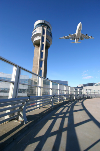 Airport radio tower in front of partly cloudy sky with departing airplane as concept for flight safety airspace surveillance and air traffic