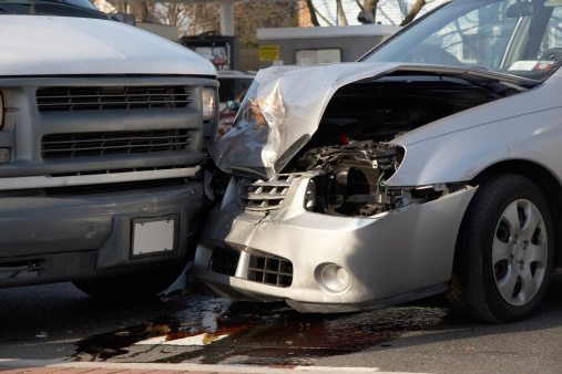 close-up of front end collision between small car and van at a busy intersection.Please Also See: