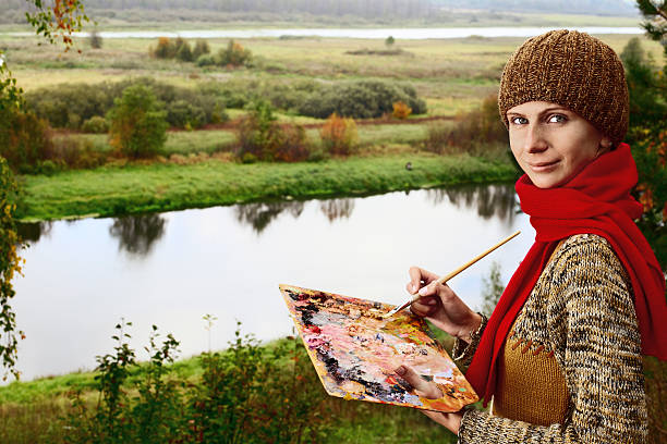 young woman draws a picture outdoors in the countryside