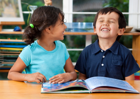 Two delighted kids enjoying a book at school. You may also like: