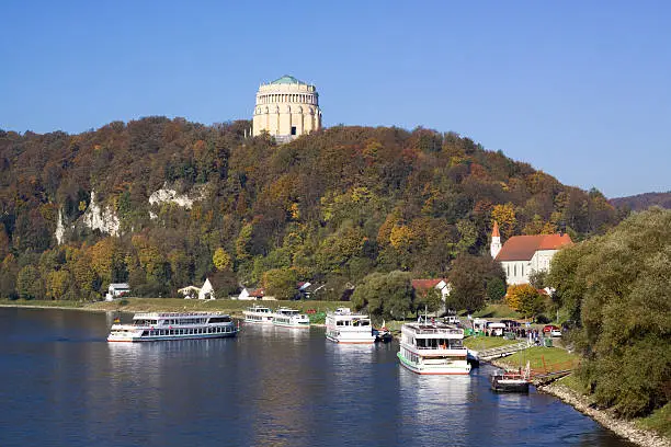 "Kelheim in Bavaria: view on danube river with ships and its landmark, the hall of liberation (Befreiungshalle) on Michelsberg at fall"