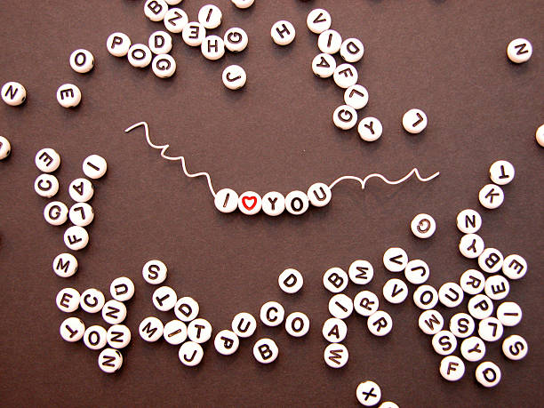 I love you beads on wire "I love (heart) you beads strung on white wire on black cardstock background. Baby bracelet beads, craft, scrapbook. Requested for Scrapbook Related" Bead stock pictures, royalty-free photos & images