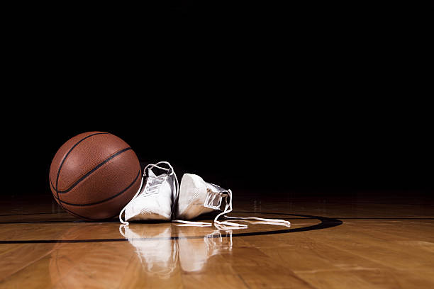 A pair of basketball shoes on a court next to a basketball stock photo