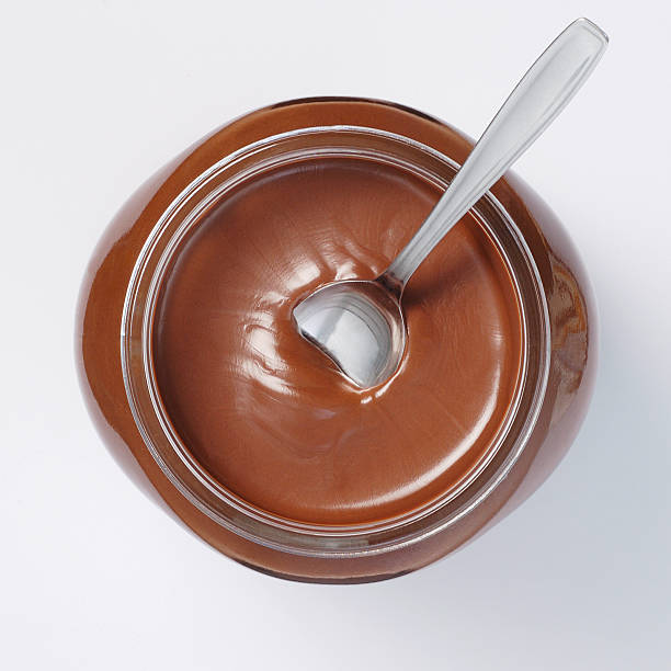 Jar of chocolate cream on white background with spoon inside stock photo
