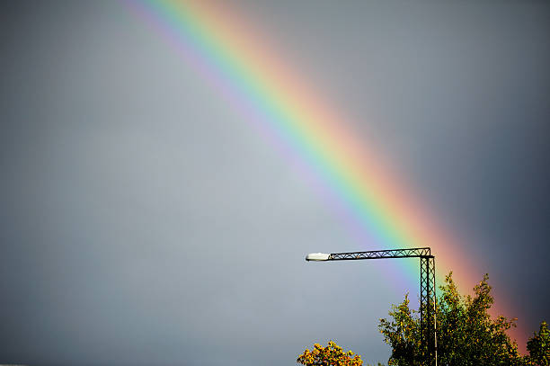 Creative artistic photograph of a streetlight with a colorful double rainbow against a black and white background. Unique fine art composition combining color and monochrome contrast, perfect for abstract, conceptual, and artistic photography.