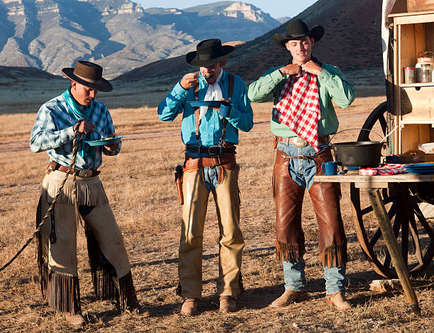 Three cowboys eat dinner at chuckwagon.Click on the following banner to see more images: