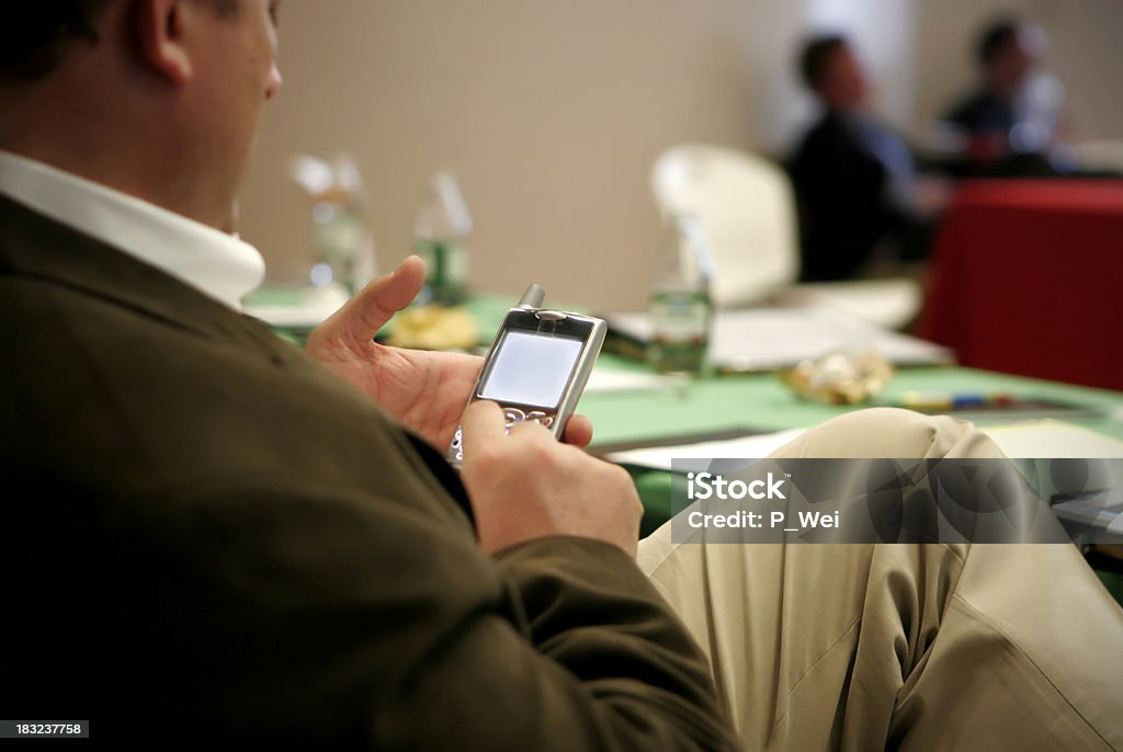 Checking email executive checking email on a PDA during a business meeting Presentation - Speech Stock Photo