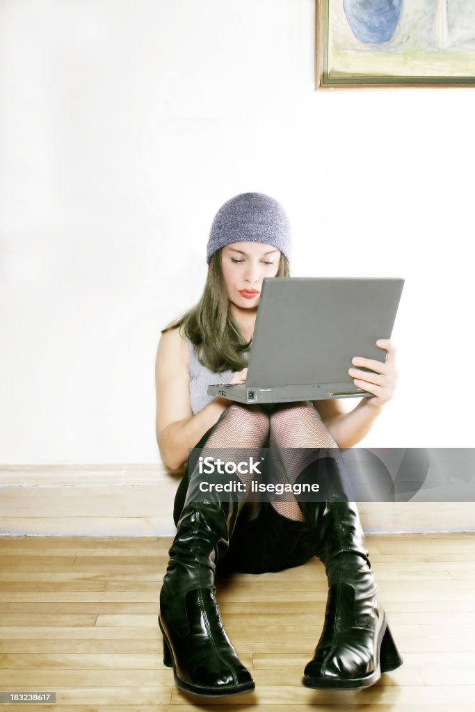 Young woman chatting.online "Young woman chatting on her laptop, sitting on the floor." Cool Attitude Stock Photo