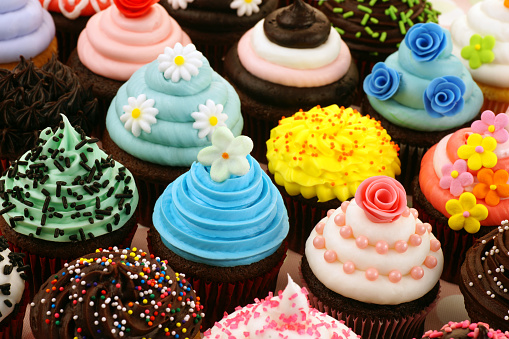 Cupcakes decorated with candy and colorful sprinkles with round candies scattered on the floor