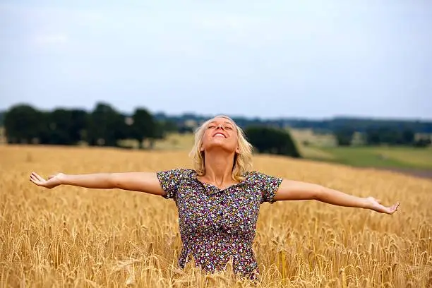 "close up of a beauty blond female teenager , standing in a golden grainfield with outstretched arms, enjoy, , raw workflow, low sharpening,"